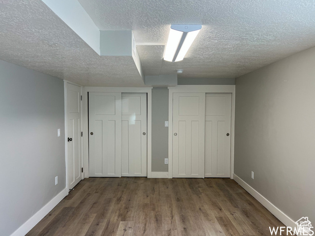 702 North 100 West Logan, UT 84321 - Photo 8 of 58 Unfurnished bedroom featuring baseboards, a textured ceiling, wood finished floors, and two closets