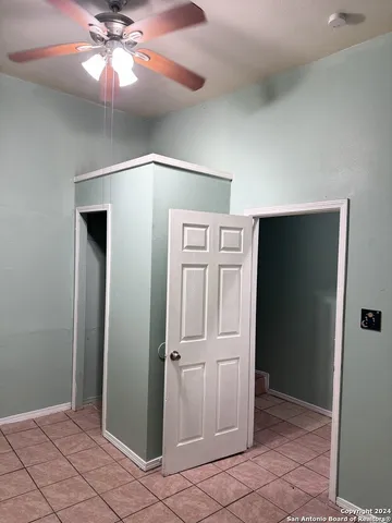 an empty room with closet and a chandelier fan