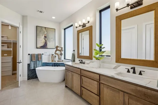 a bathroom with a double vanity sink mirror and bathtub