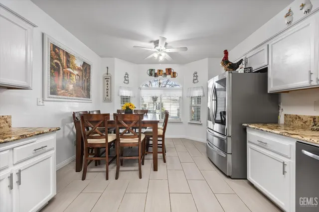 a kitchen with stainless steel appliances a dining table chairs stove refrigerator and cabinets