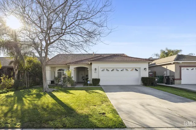 a view of a white house with a large tree and yard
