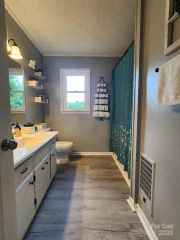 a bathroom with a sink a toilet a mirror and a window