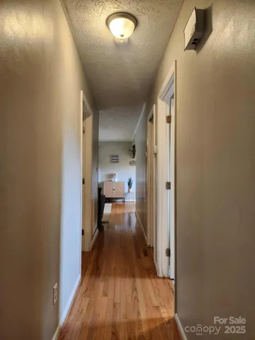 a view of a hallway with wooden floor a bathroom and a sink