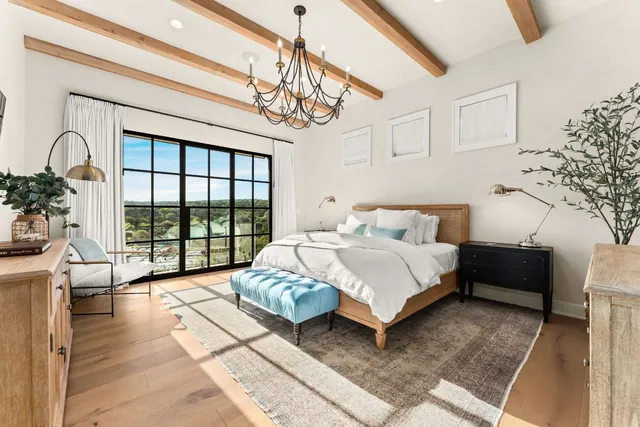 a spacious bedroom with a bed a chandelier and large window
