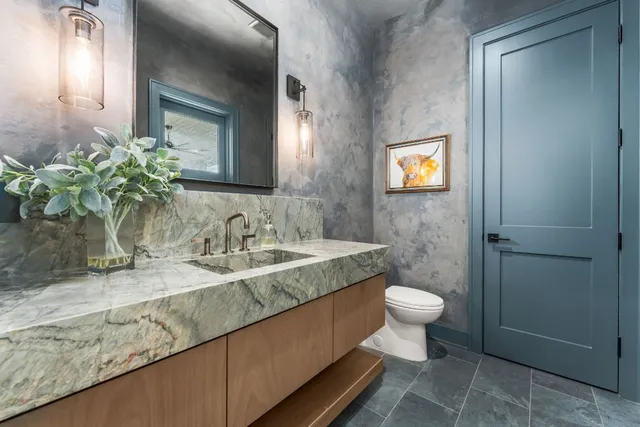 a bathroom with a granite countertop sink a toilet and a mirror
