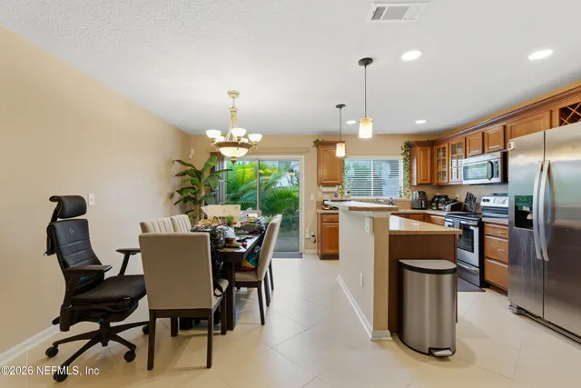 a kitchen with kitchen island a dining table chairs stainless steel appliances and cabinets