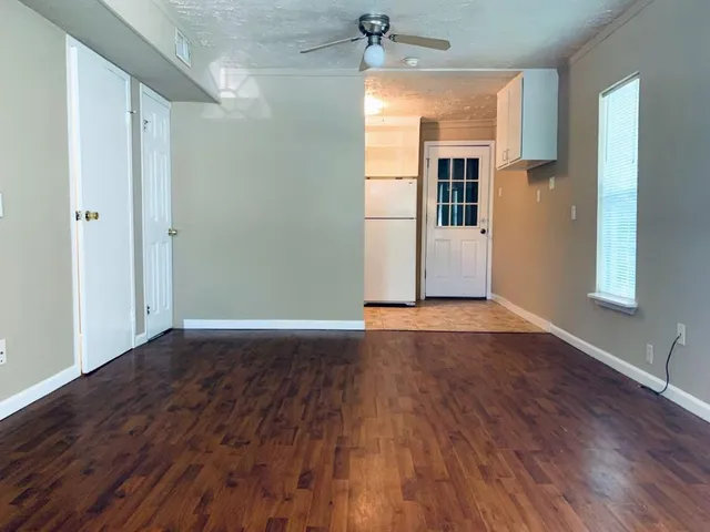 an empty room with wooden floor and windows
