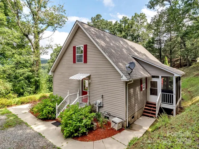 a view of a house with a yard plants and a large tree