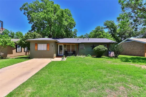 a front view of a house with a yard and trees