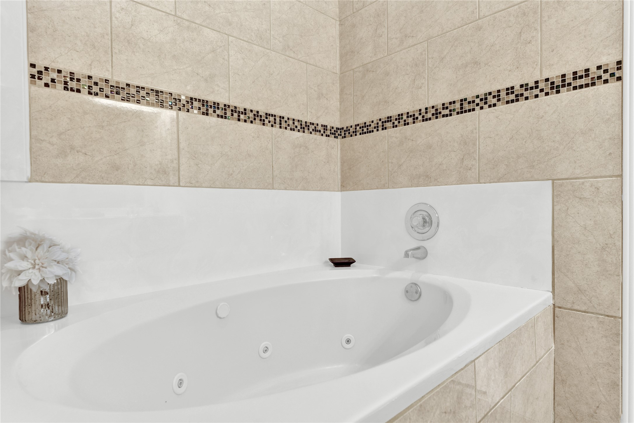 14420 Walters Road, Unit 16 Houston, TX 77014 - Photo 13 of 27 This photo showcases a luxurious bathroom with a corner jetted tub, surrounded by elegant beige tiles accented with a mosaic border, creating a serene and inviting space for relaxation.