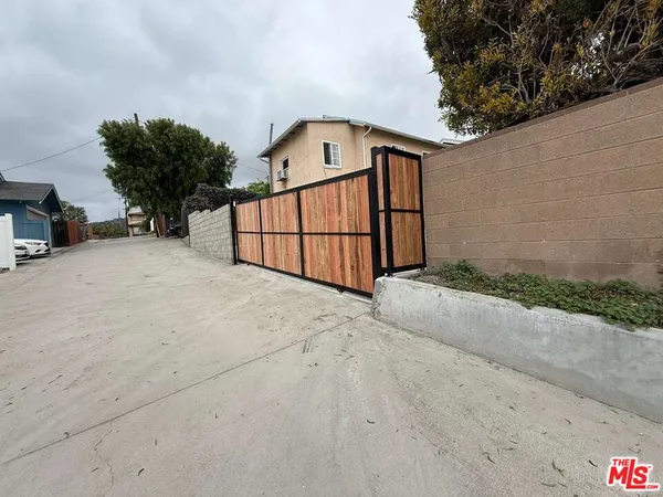 a view of backyard with small garden and wooden fence