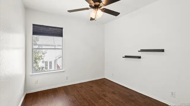 an empty room with a window and a ceiling fan