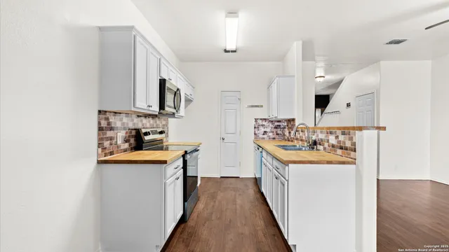 a kitchen with stainless steel appliances granite countertop a sink a stove a refrigerator and island with wooden floor