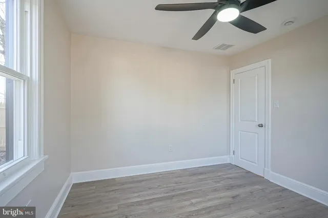an empty room with wooden floor cabinet and windows