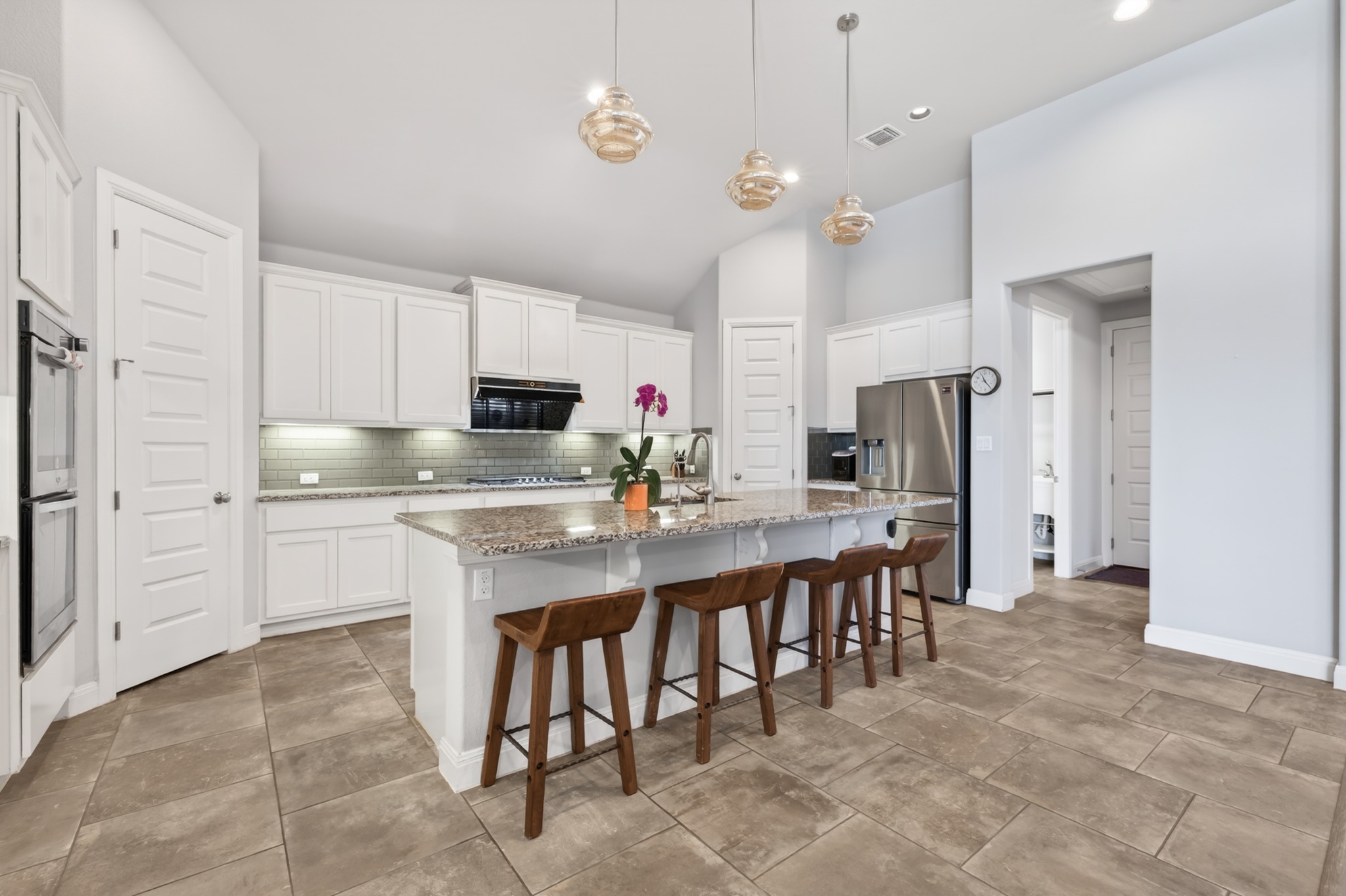 4105 Haight Street Round Rock, TX 78681 - Photo 17 of 40 Modern kitchen featuring a central island with a granite-style countertop, white cabinetry, and stainless steel appliances including a double oven and refrigerator