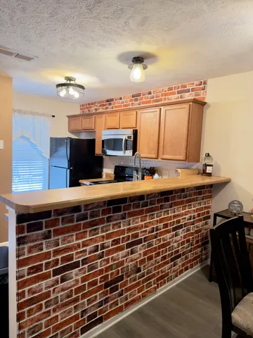 a view of kitchen with stainless steel appliances wooden floor