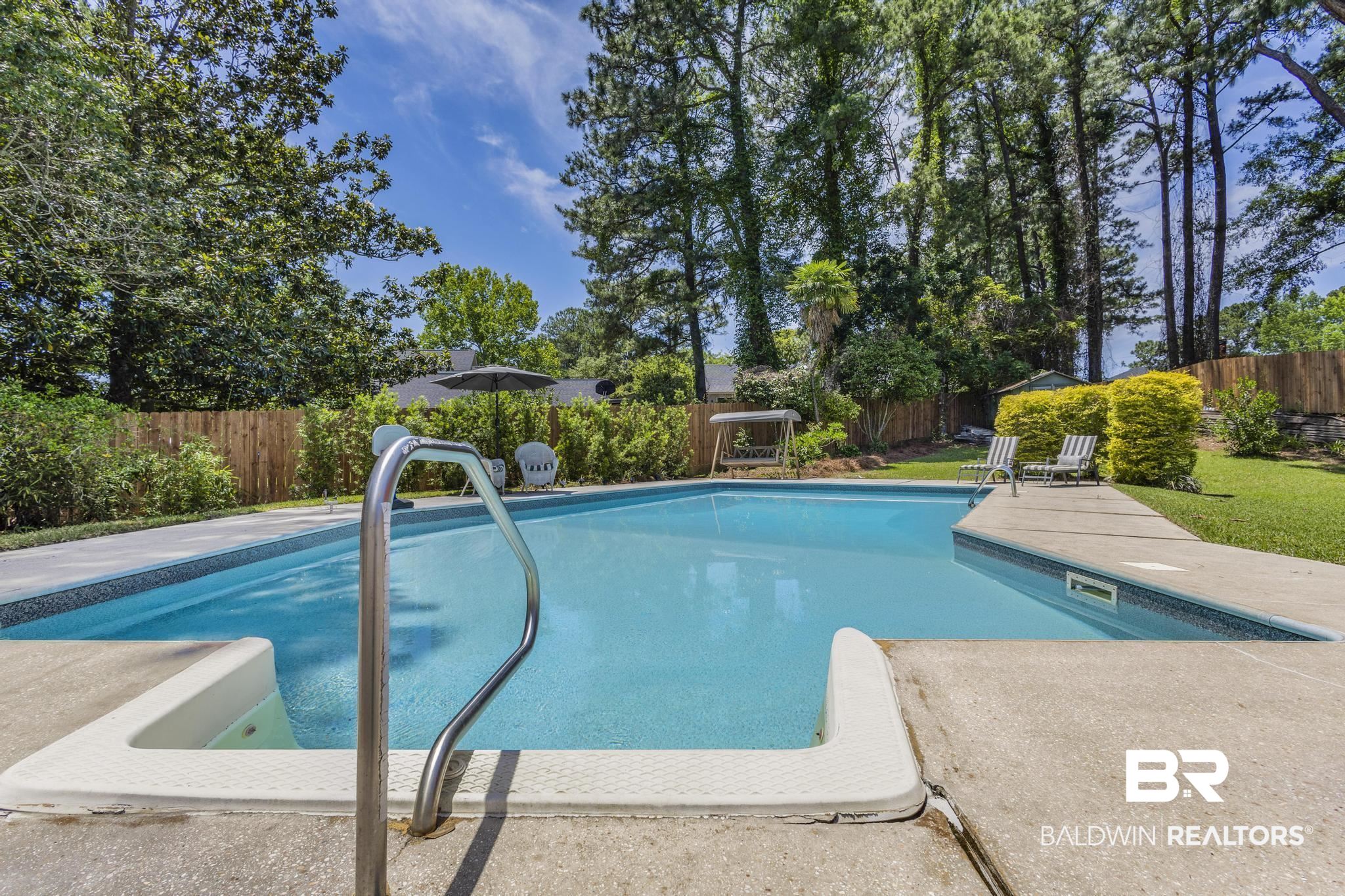 83 Caisson Trace Daphne, AL 36527 - Photo 57 of 63 Backyard swimming pool featuring concrete decking, a stainless steel handrail, and a tile border
