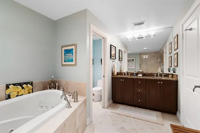 a bathroom with a tub a double vanity sink and a mirror