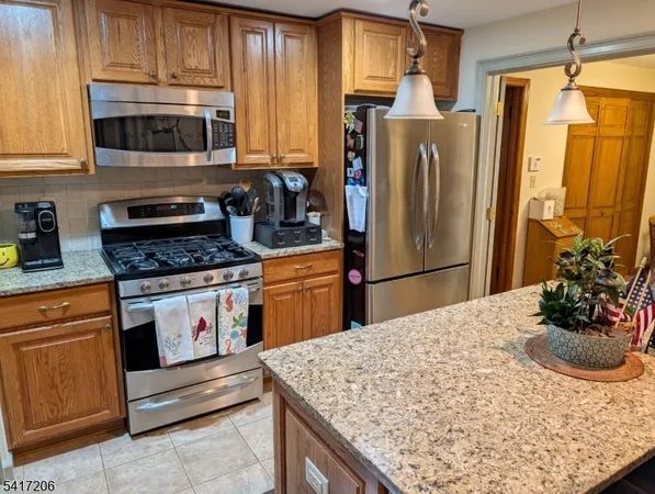 a kitchen with stainless steel appliances granite countertop a refrigerator sink stove microwave and cabinets