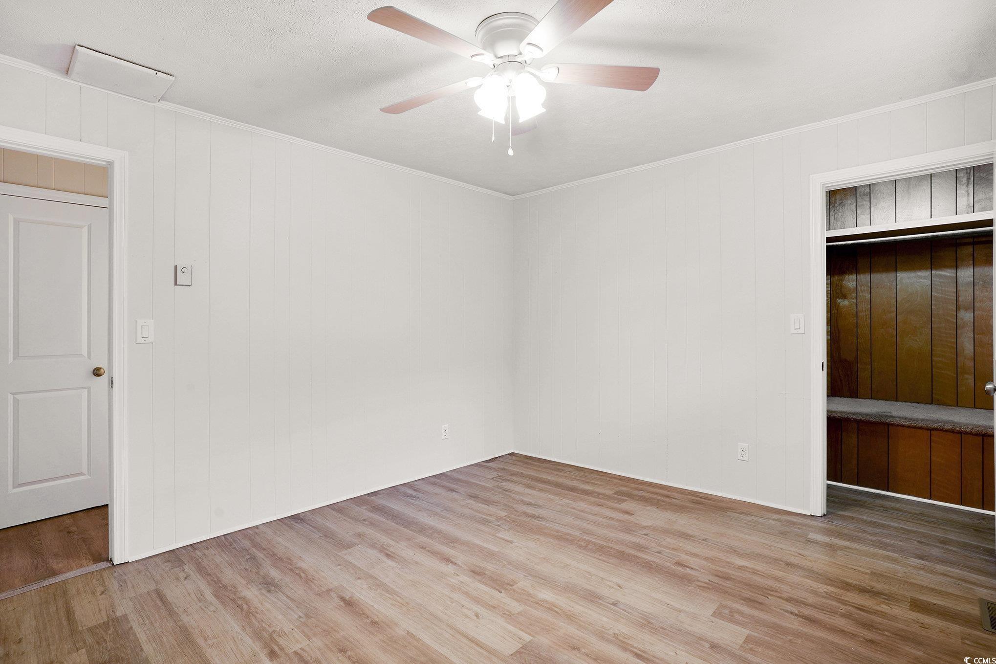 603 Maple Street Myrtle Beach, SC 29577 - Photo 15 of 40 Unfurnished bedroom with light wood-type flooring, ceiling fan, and wood walls