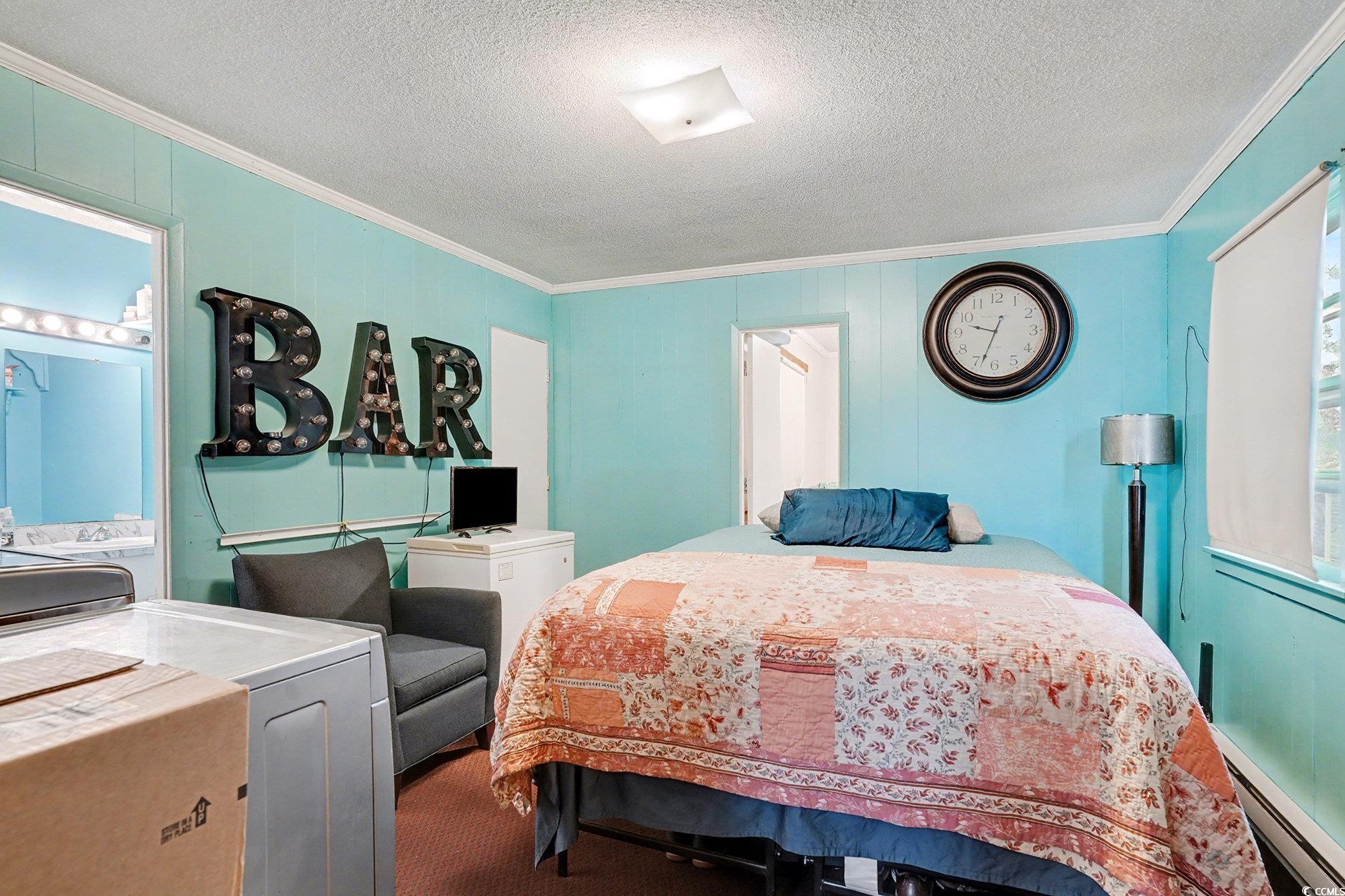 603 Maple Street Myrtle Beach, SC 29577 - Photo 23 of 40 Bedroom featuring baseboard heating, washer / dryer, crown molding, carpet flooring, and a textured ceiling