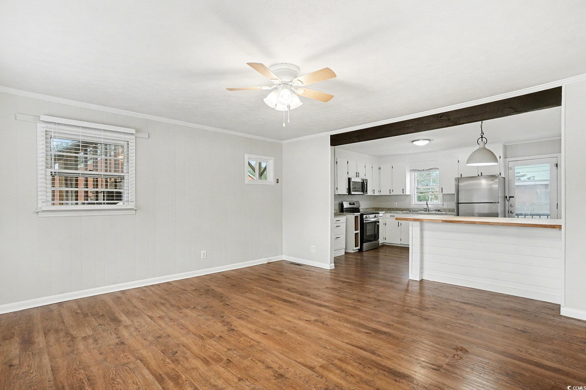 603 Maple Street Myrtle Beach, SC 29577 - Photo 5 of 40 Unfurnished living room featuring dark wood-style flooring, crown molding, and a ceiling fan
