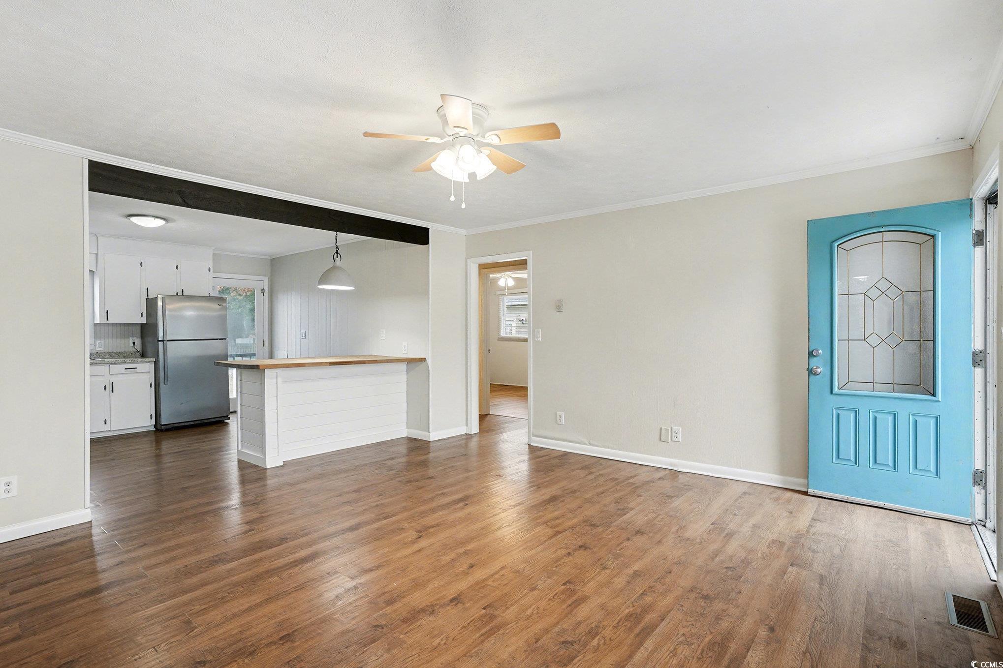 603 Maple Street Myrtle Beach, SC 29577 - Photo 6 of 40 Unfurnished living room featuring ornamental molding, dark wood-style flooring, and a ceiling fan