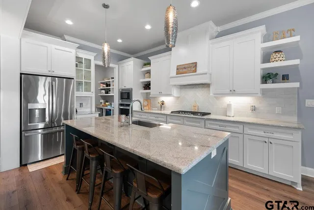 a kitchen with stainless steel appliances granite countertop a table chairs sink refrigerator and microwave