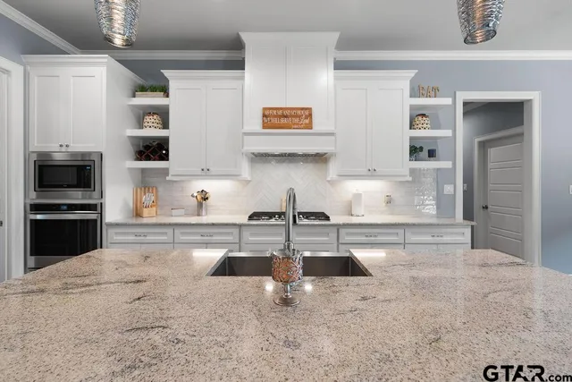 a kitchen with stainless steel appliances granite countertop a sink and a stove