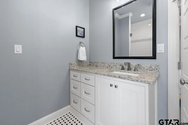 a bathroom with a granite countertop sink and a mirror