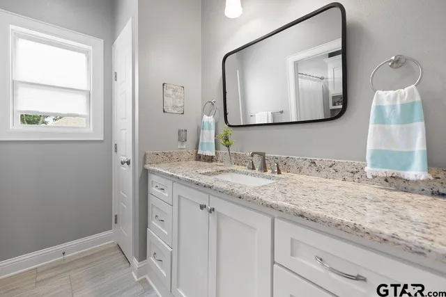 a en suite bathroom with a granite countertop sink and a mirror
