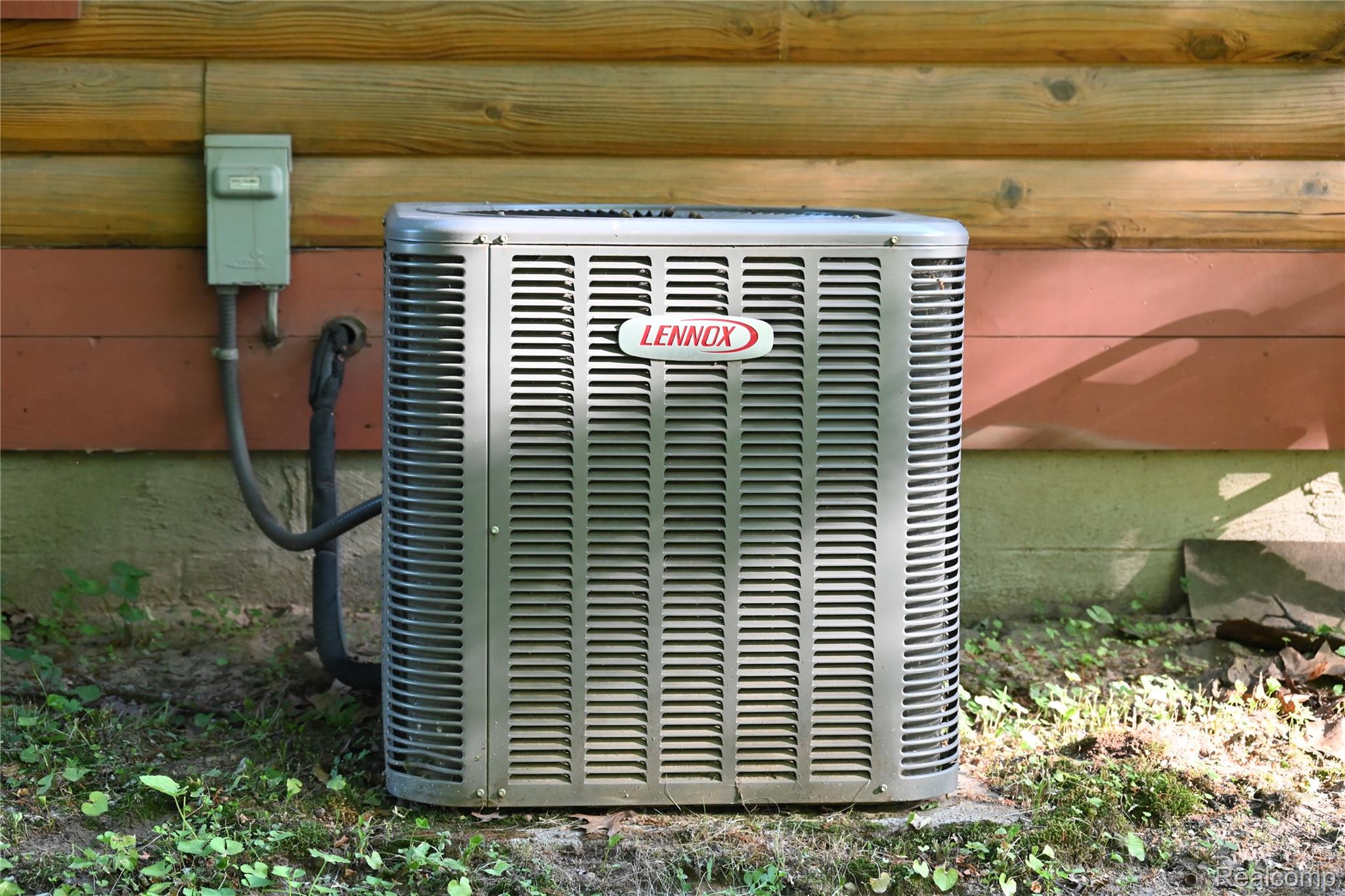 16501 Hannan Road Romulus, MI 48174 - Photo 20 of 20 Lennox air conditioning unit on a concrete pad, against a log-style exterior with a foundation wall