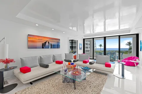a living room with furniture and floor to ceiling window kitchen view