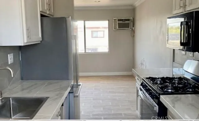 a kitchen with stainless steel appliances a refrigerator a stove and a sink with wooden floor