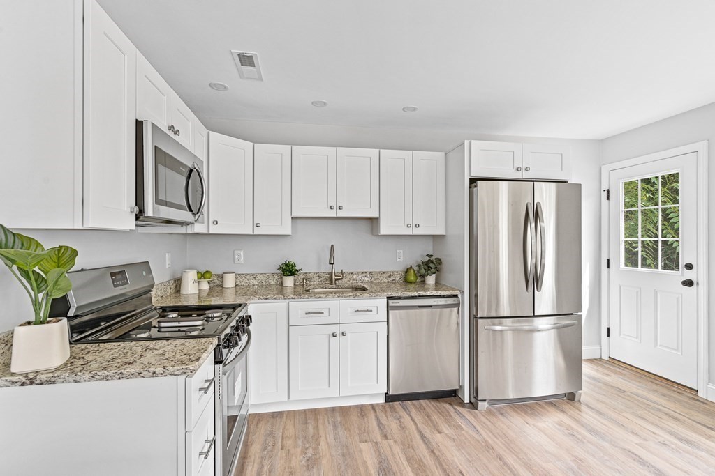 543 Andover Street, Unit 6 Lawrence, MA 01843 - Photo 8 of 27 a kitchen with stainless steel appliances granite countertop a refrigerator a stove a sink dishwasher and white cabinets with wooden floor