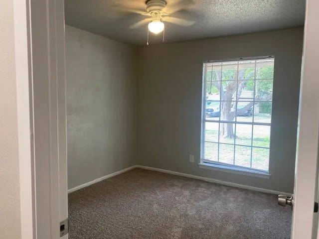 an empty room with a window and a fan