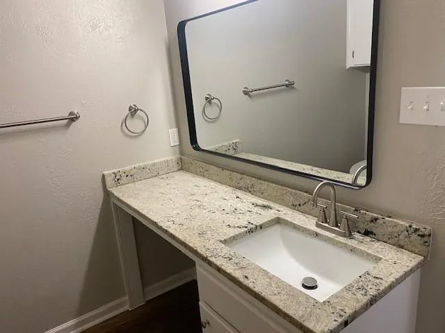 a bathroom with a granite countertop sink and a mirror