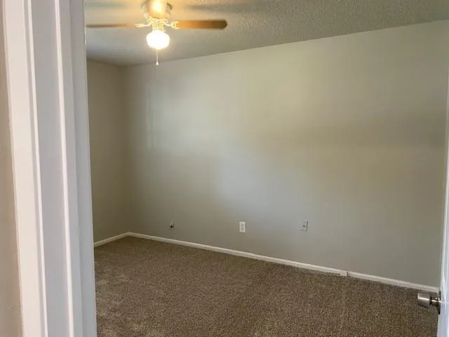 an empty room with a chandelier fan and closet