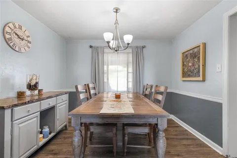 a dining room with wooden floor a chandelier a wooden table and chairs