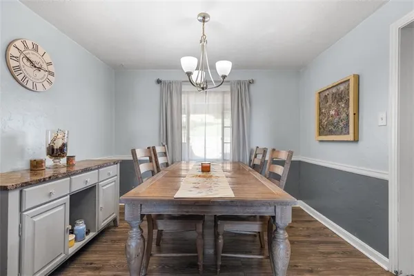 a dining room with wooden floor a chandelier a wooden table and chairs