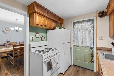 a kitchen with a refrigerator a stove a sink dishwasher and a dining table with wooden cabinet