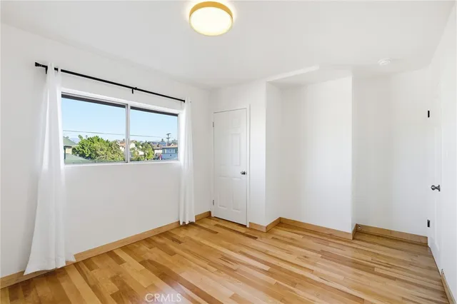 a view of a bedroom with wooden floor and small window