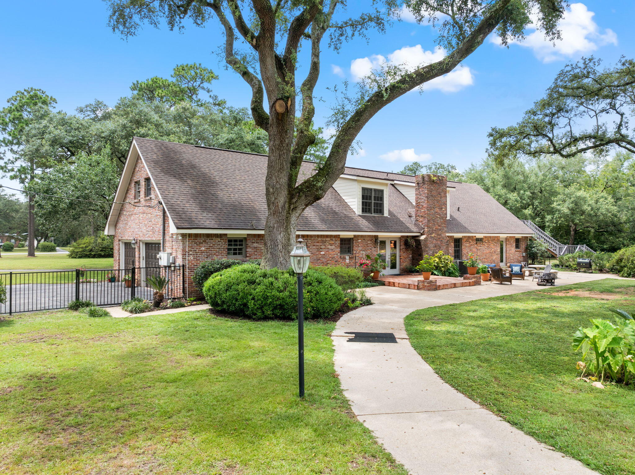 a view of a house with a big yard potted plants and a large tree