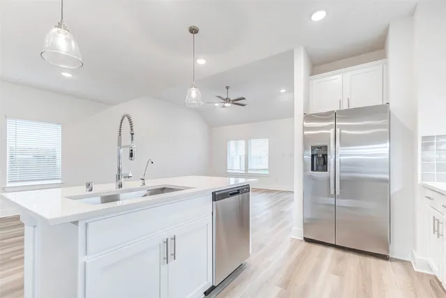 a kitchen with a sink refrigerator and wooden floor
