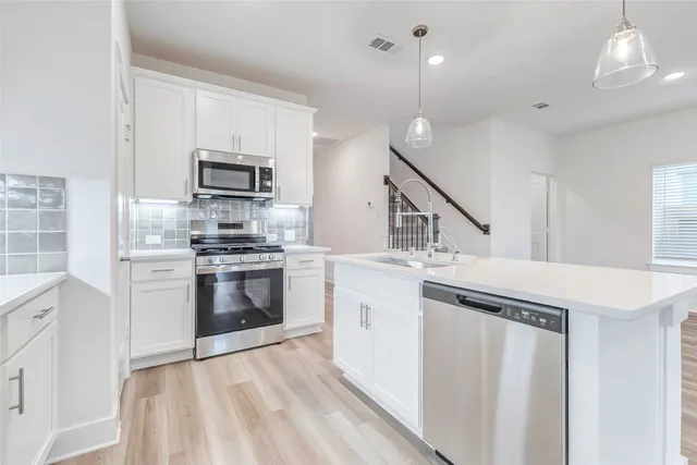 a kitchen with stainless steel appliances a stove a sink and a refrigerator
