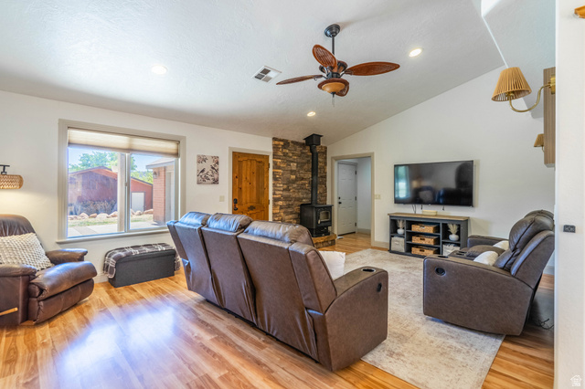 1504 Rome Way Apple Valley, UT 84737 - Photo 4 of 22 Bright living space featuring wood-finish flooring, a stone accent wall with a wood-burning stove, and a vaulted ceiling with a ceiling fan