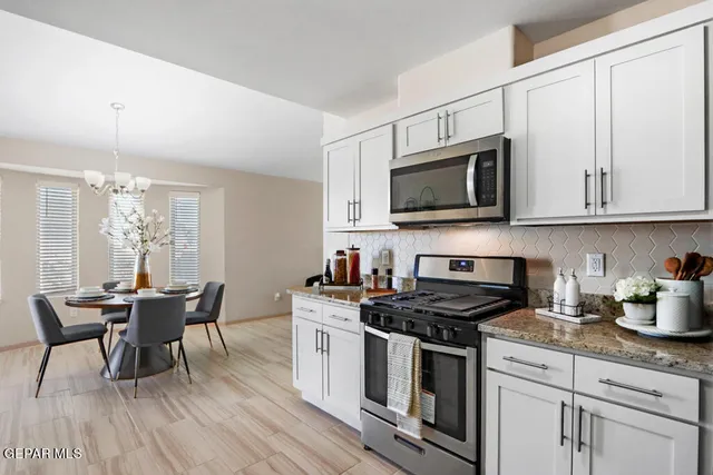 a kitchen with stainless steel appliances a white stove top oven a sink dishwasher a dining table and chairs with wooden floor