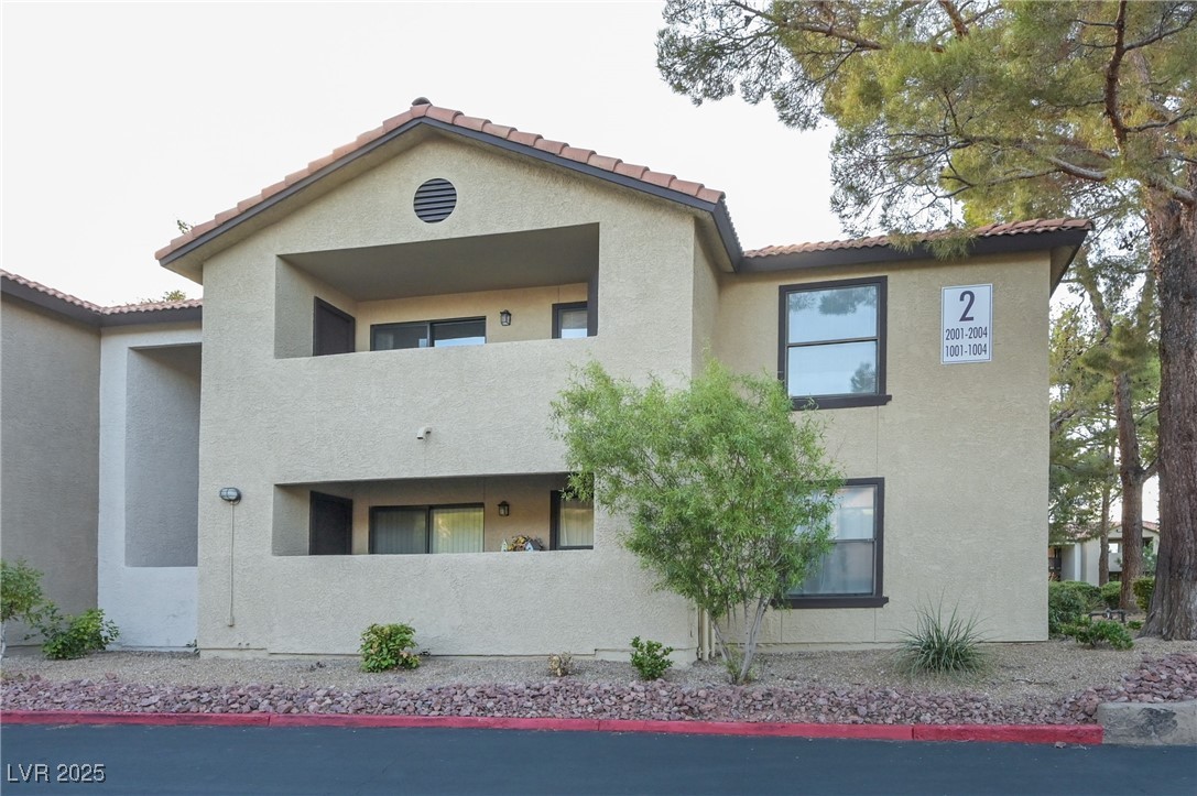 Front of property with stucco siding, a tile roof, and a balcony