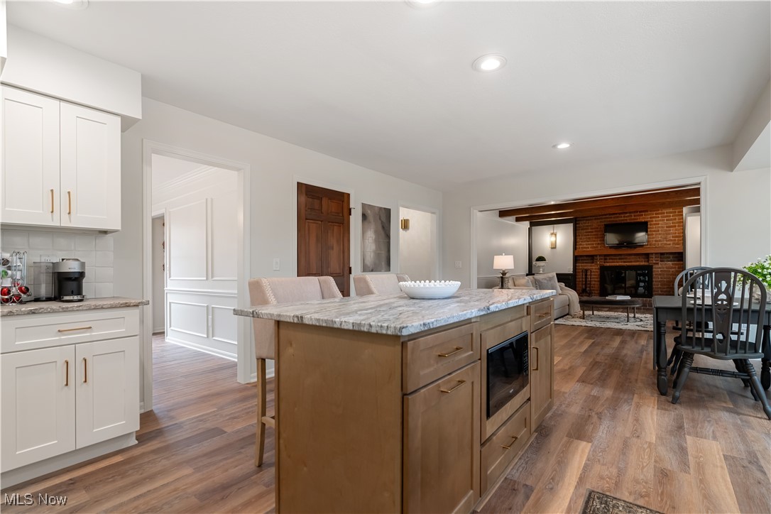4124 Bramshaw Road Northwest Canton, OH 44718 - Photo 12 of 40 Kitchen with a kitchen bar, white cabinetry, decorative backsplash, and wood finished floors