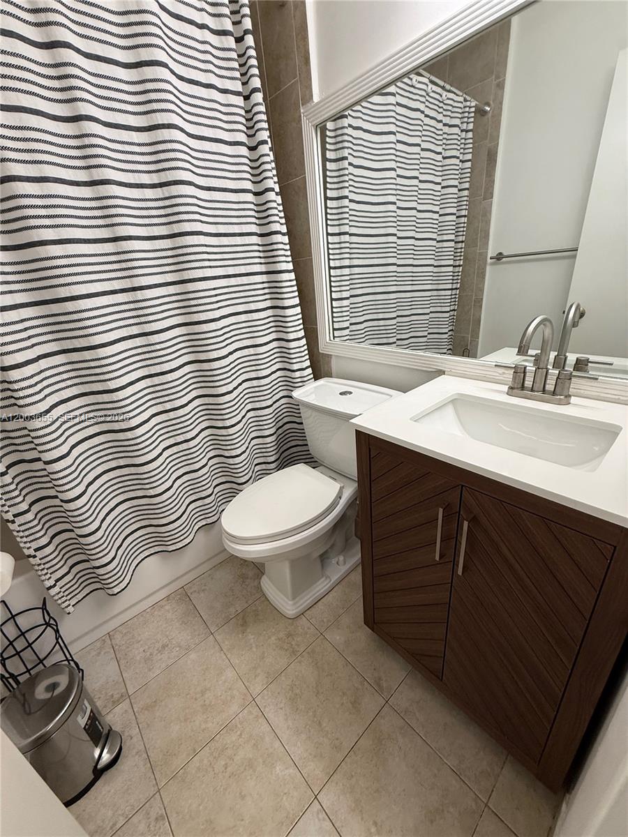 203 Riviera Circle, Unit 203 Weston, FL 33326 - Photo 20 of 30 a bathroom with a sink a toilet a mirror and shower curtain
